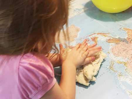 child squashing white playdough on a table